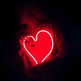 Eine junge Frau hält ein leuchtendes, rotes Herz