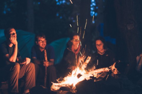 Freunde sitzen an einem Lagerfeuer.