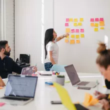 Gruppe arbeitet gemeinsam mit Laptops und Postits