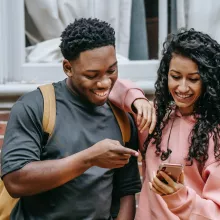 Ein Jugendlicher und eine Jugendliche schauen gemeinsam auf ein Smartphone