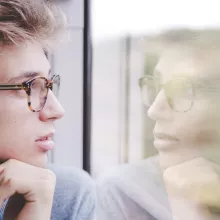Jugendlicher sieht sein Spiegelbild im Zugfenster